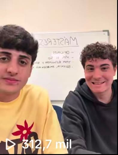 Dos estudiantes explicando la oferta de másteres de la UMH ante una pizarra
